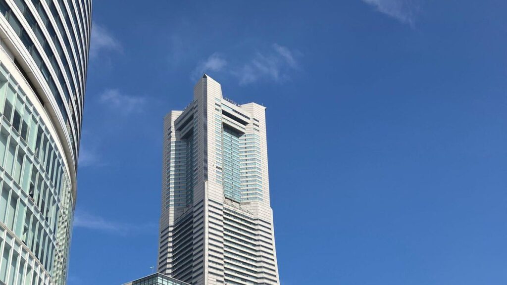青空を背景にそびえる横浜ランドマークタワーと周辺のビル群
