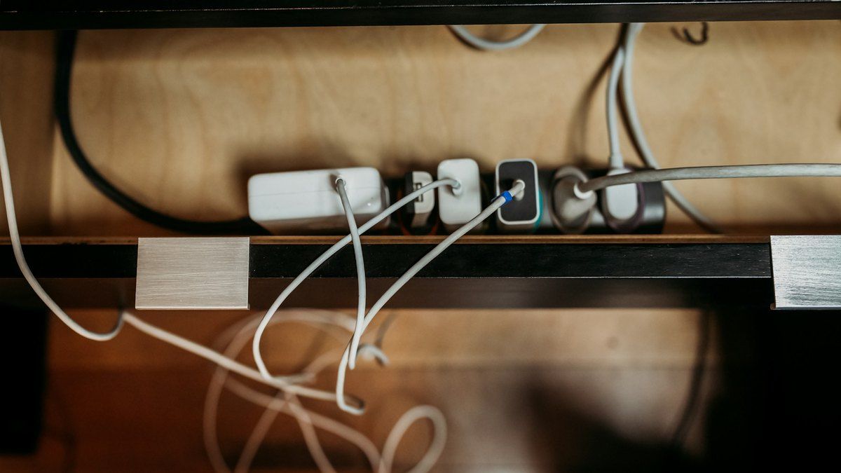 カフェのテーブル下に設置された電源タップに複数の充電アダプターが挿さっている様子